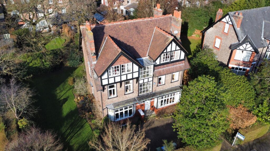 An aerial view of a large home surrounded by garden and greenery.