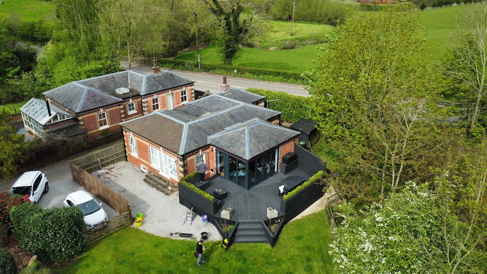 Aerial view of a detached roadside bungalow, surrounded by green fields.