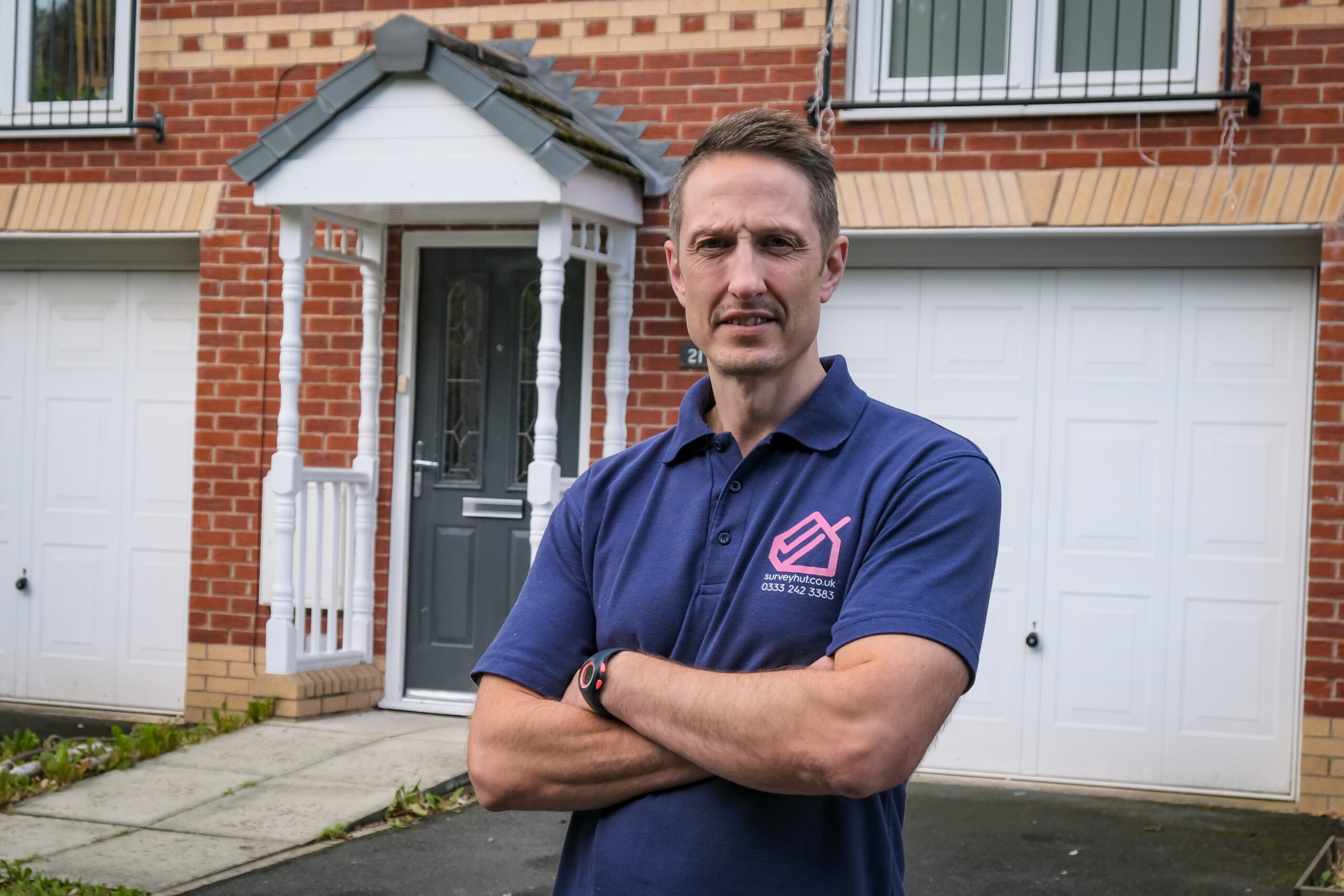 James raspin in a survey hut polo shirt outside a house